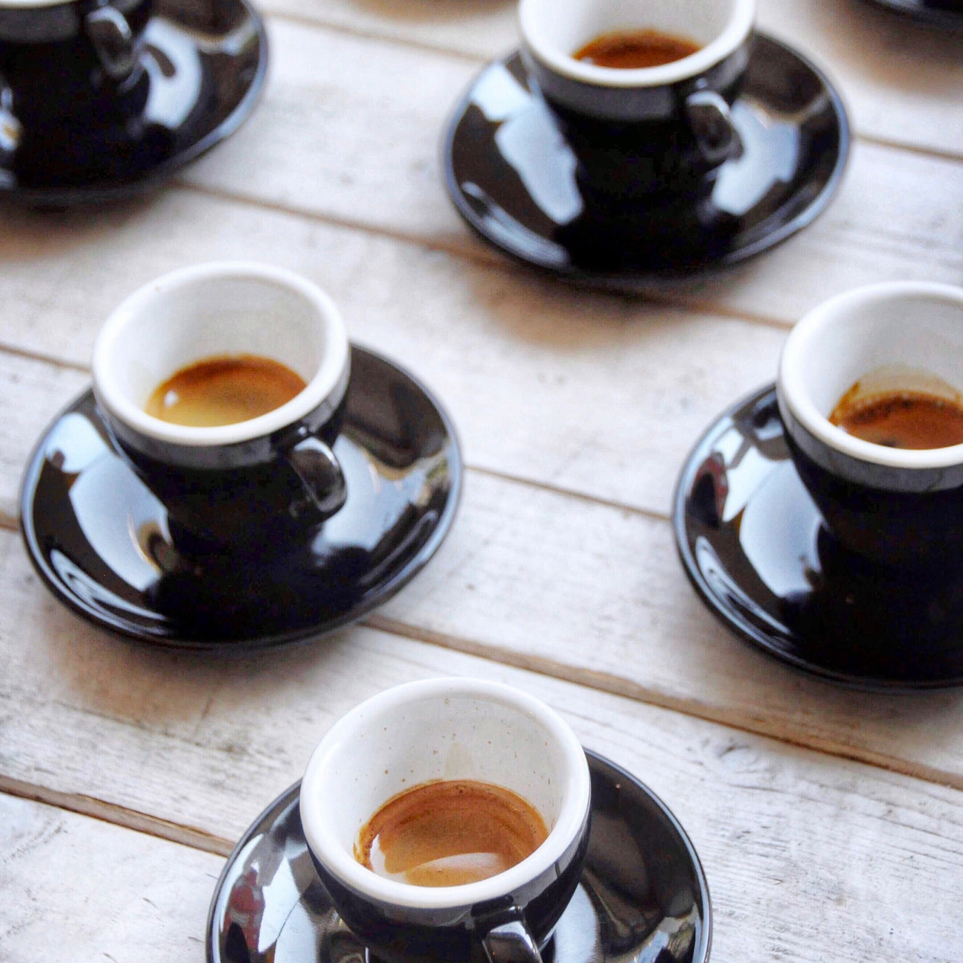 5 cups of espresso coffee in black cups on wooden table. 